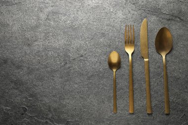 Gri masadaki altın çatal bıçak takımı, düz. Metin için boşluk