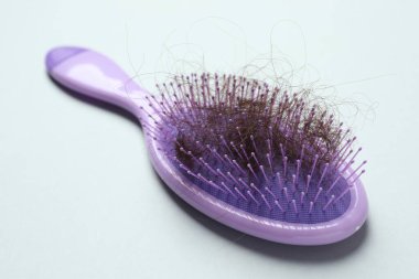 Gri arka planda saçı dökülmüş bir fırça, yakın plan. Alopecia sorunu