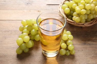 Bardakta lezzetli meyve suyu ve ahşap masada taze üzümler, yakın plan.