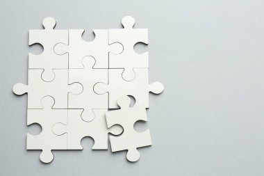 Gri arka planda beyaz yapboz parçaları, üst manzara. Metin için boşluk