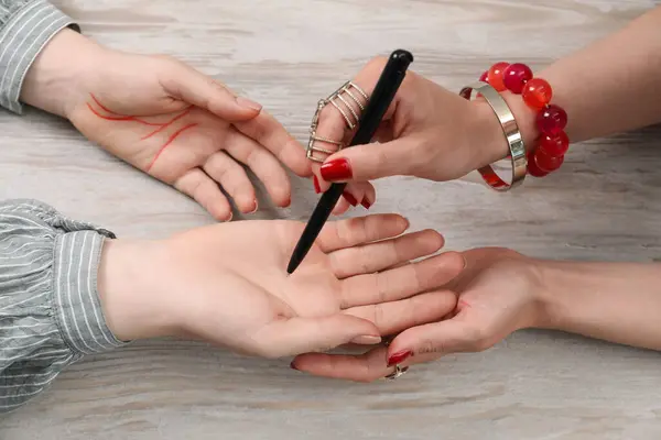 stock image Fortune teller reading lines on woman's palm at wooden table, closeup. Chiromancy