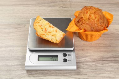 Mutfak terazisi, açık ahşap masa üzerindeki kek parçasıyla yakın plan.