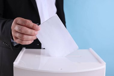 Adam oyunu açık mavi arkaplana karşı sandığa koyuyor.