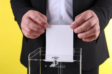 Adam oyunu sarı arka plana karşı sandığa koyuyor, yakın plan.