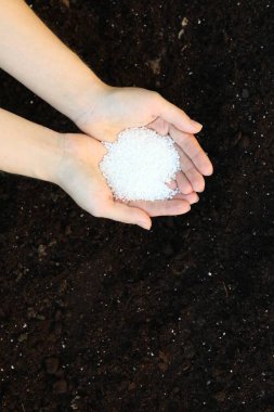 Toprağı gübreyle gübreleyen bir kadın.