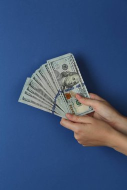 Mavi arka planda dolar banknotları olan kadın, yakın plan.
