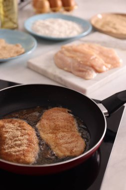 Schnitzels cooking in frying pan on stove, closeup clipart