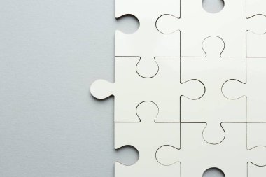 Gri arka planda beyaz yapboz parçaları, üst manzara. Metin için boşluk
