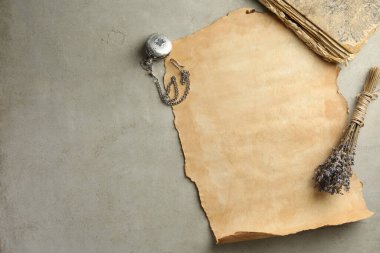 Eski parşömen kağıdı, lavanta çiçekleri, antika kitap ve cep saati gri masanın üstünde, düz yatıyordu.