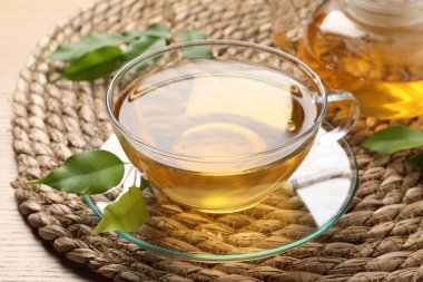 Yeşil çayı fincanda tazeleyen ve ahşap masada yapraklar, yakın plan