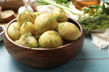 Lezzetli, taze haşlanmış patatesler, açık mavi ahşap masada dereotlu, yakın plan.