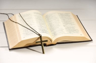 Beyaz ahşap masada zincir ve İncil 'le yan yana, yakın plan. Hıristiyanlık Dini