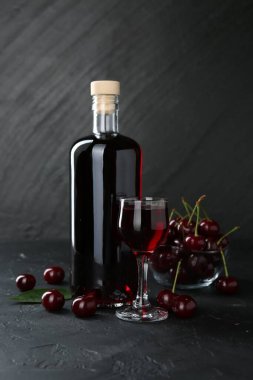 Lezzetli kiraz likörü ve böğürtlen siyah masada.