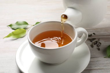 Gri ahşap masada serinletici yeşil çayı fincana dök, kapat.