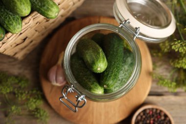 Ev yapımı turşu. Kavanozda taze salatalıklar, ahşap masada dereotu ve biber, düz uzanmış.