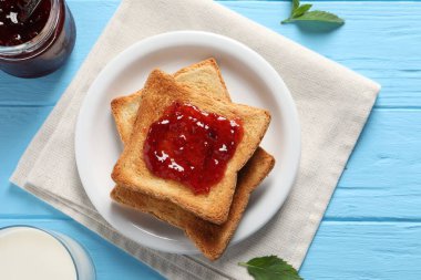 Lezzetli tostlar reçelli ve süt açık mavi ahşap masada, düz yatıyordu.