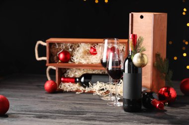 Bottles of wine, glasses, wooden boxes, fir twigs and Christmas balls on table