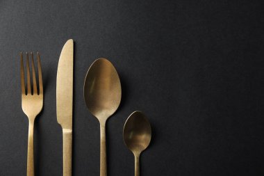 Siyah arka planda altın çatal bıçak takımı, düz. Metin için boşluk