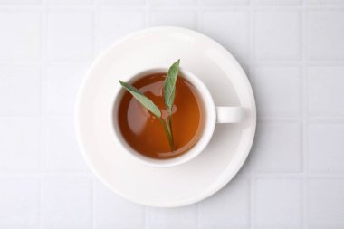 Aromatik bitki çayı, beyaz fayanslı masada adaçayı, üst manzara.