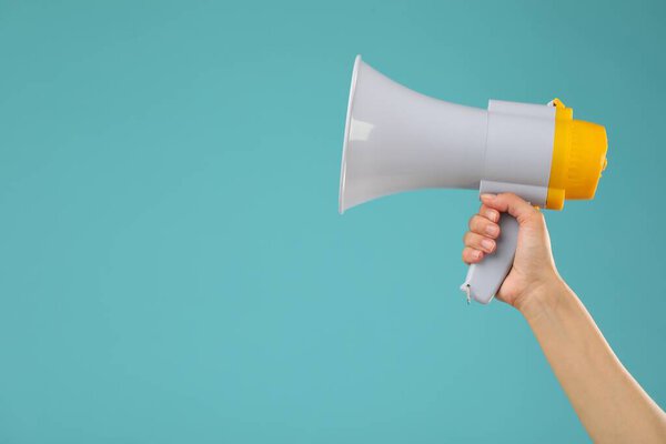 Woman holding megaphone speaker on blue background, closeup. Space for text