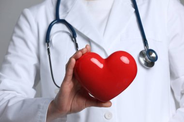 Gri arka planda kırmızı kalpli doktor, yakın plan.