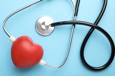 Açık mavi arkaplanda stetoskop ve kırmızı kalp, üst görünüm