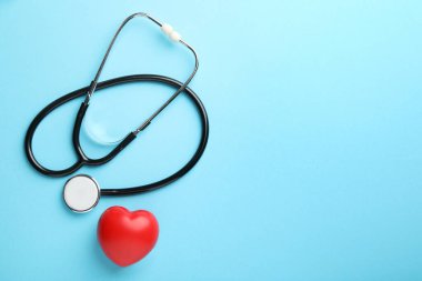 Stetoskop ve açık mavi arka planda kırmızı kalp, üst manzara. Metin için boşluk