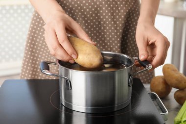 Ocakta patatesi tencereye koyan kadın, yakın plan.