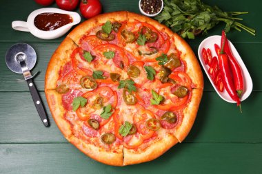 Lezzetli pizza Diablo, malzemeler ve keski yeşil ahşap masa, düz uzanma