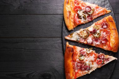 Siyah ahşap masanın üstünde leziz pizza parçaları olan tahta masa, üst manzara. Metin için boşluk