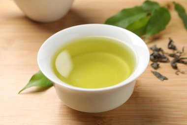 Yeşil çayı fincanda tazeleyen ve ahşap masada yapraklar, yakın plan