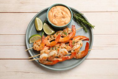 Beyaz ahşap masada servis edilen lezzetli ızgara karidesli şişler.