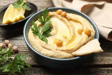 Zeytinyağlı lezzetli humus, nohut ve pide ahşap masada, yakın plan.
