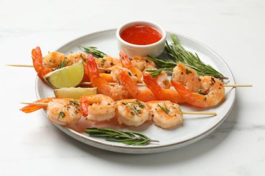 Beyaz mermer masada servis edilen lezzetli ızgara karidesli şişler.