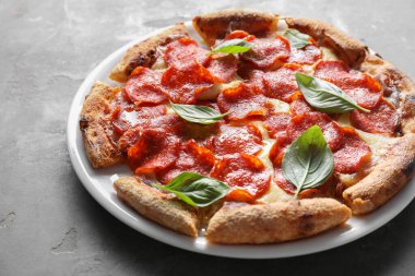 Gri masadaki fesleğenli lezzetli biberli pizza.