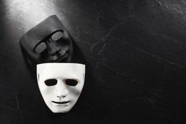 Siyah tahta yüzeyde plastik yüz maskeleri, yazı için üst görünüm ve boşluk. Tiyatro performansı