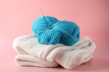 Pembe arka planda örgü iğneleri, desen örneği ve süveter ile iplik kabuğu, yakın plan