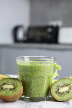 Lezzetli yeşil smoothie ve malzemeler beyaz masada.
