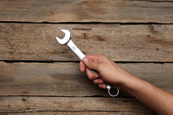 Автомеханик с гаечным ключом за деревянным столом, крупным планом