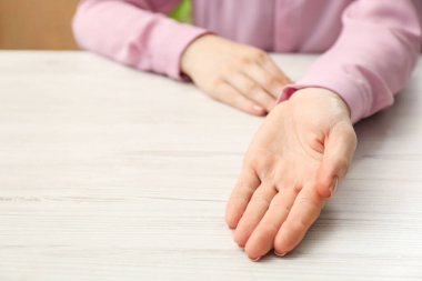 Şiromantizm ve kehanet. Beyaz ahşap masada avuç içi gösteren bir kadın, yakın plan. Metin için boşluk