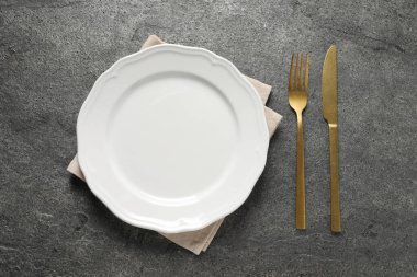 Altın çatal bıçak, tabak ve peçete gri masa, üst manzara