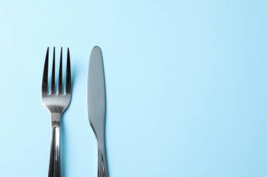 Açık mavi arka planda gümüş çatal bıçak takımı, üst manzara. Metin için boşluk