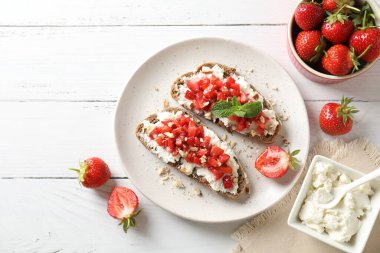 Ricotta peyniri, doğranmış çilek ve beyaz ahşap masada nane şekeri.
