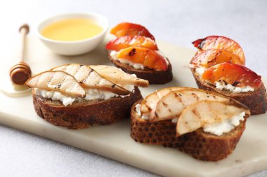 Açık gri masada ricotta peynirli ve ballı nefis bruschettalar, yakın plan.