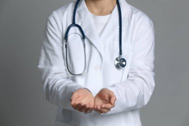 Doktor gri arka planda bir şey tutuyor, yakın plan.