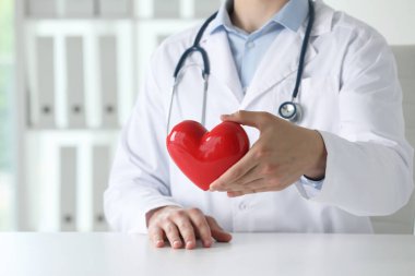 Klinikteki beyaz masada kırmızı kalpli doktor, yakın plan.