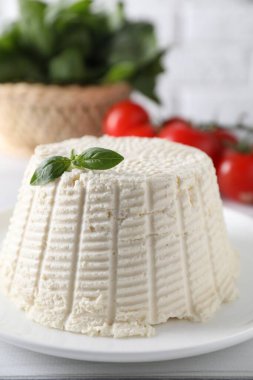 Beyaz masada fesleğenli taze ricotta (krem peynir), yakın plan.