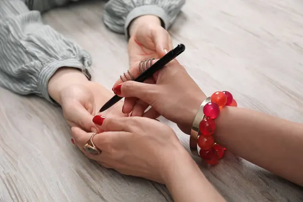 stock image Fortune teller reading lines on woman's palm at wooden table, closeup. Chiromancy