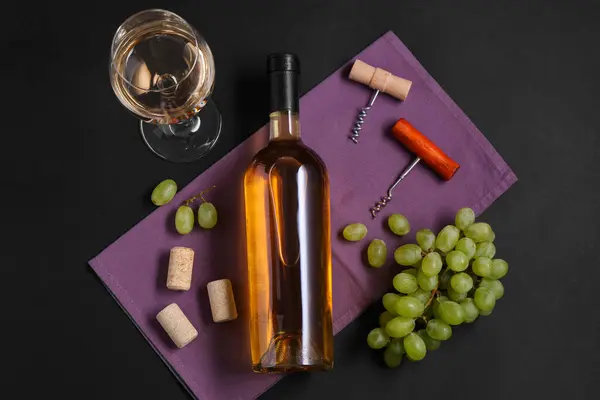 Stock image Corkscrews, wine, grapes and corks on black background, flat lay