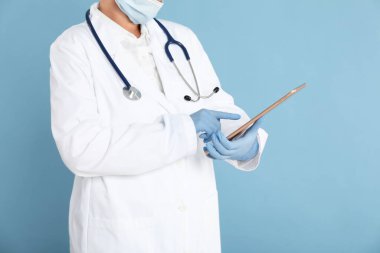 Açık mavi arkaplanda tableti olan doktor, görüntüyü kapat